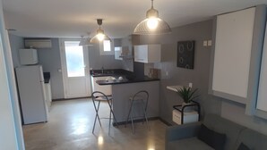 A modern kitchen with a dining area, a sofa, and a small table. - Appartement Quartier Calme (Perpignan)