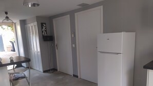 A kitchen with a white refrigerator, a bar stool, and a ceiling light fixture. - Appartement Quartier Calme (Perpignan)