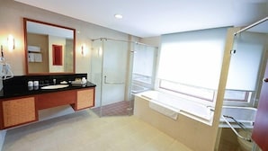 Une salle de bain moderne avec un grand miroir, un plan de toilette noir, une baignoire et un espace douche.
