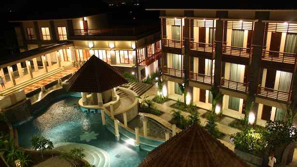 Un hôtel doté d’une piscine, de plusieurs balcons et d’un espace extérieur bien éclairé la nuit.
