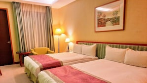 Une chambre d’hôtel avec deux lits, une chaise, une lampe et un tableau au mur.