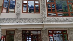 A multi-story building with a brick facade, large windows, and a ground-level entrance with a door and glass panels. - Mash Denzong Shiron (Gangtok)