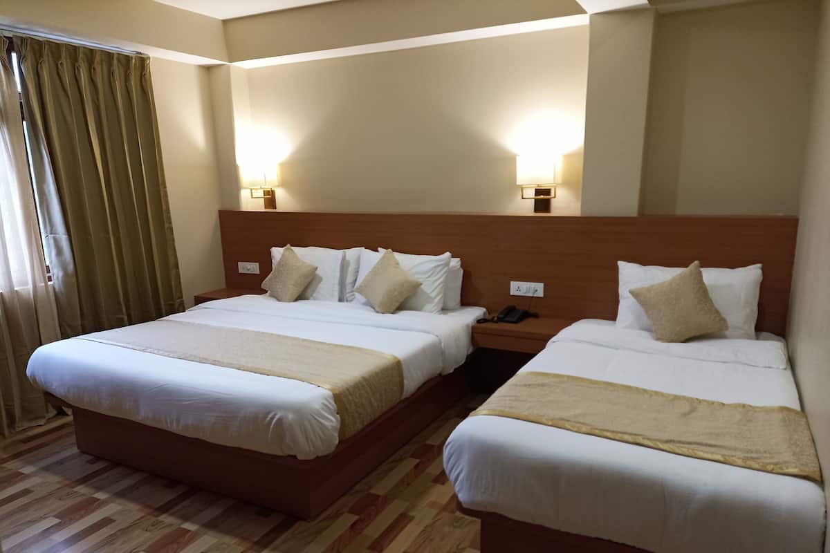 Quarto de hotel com duas camas, piso de madeira e mesa de cabeceira com telefone.