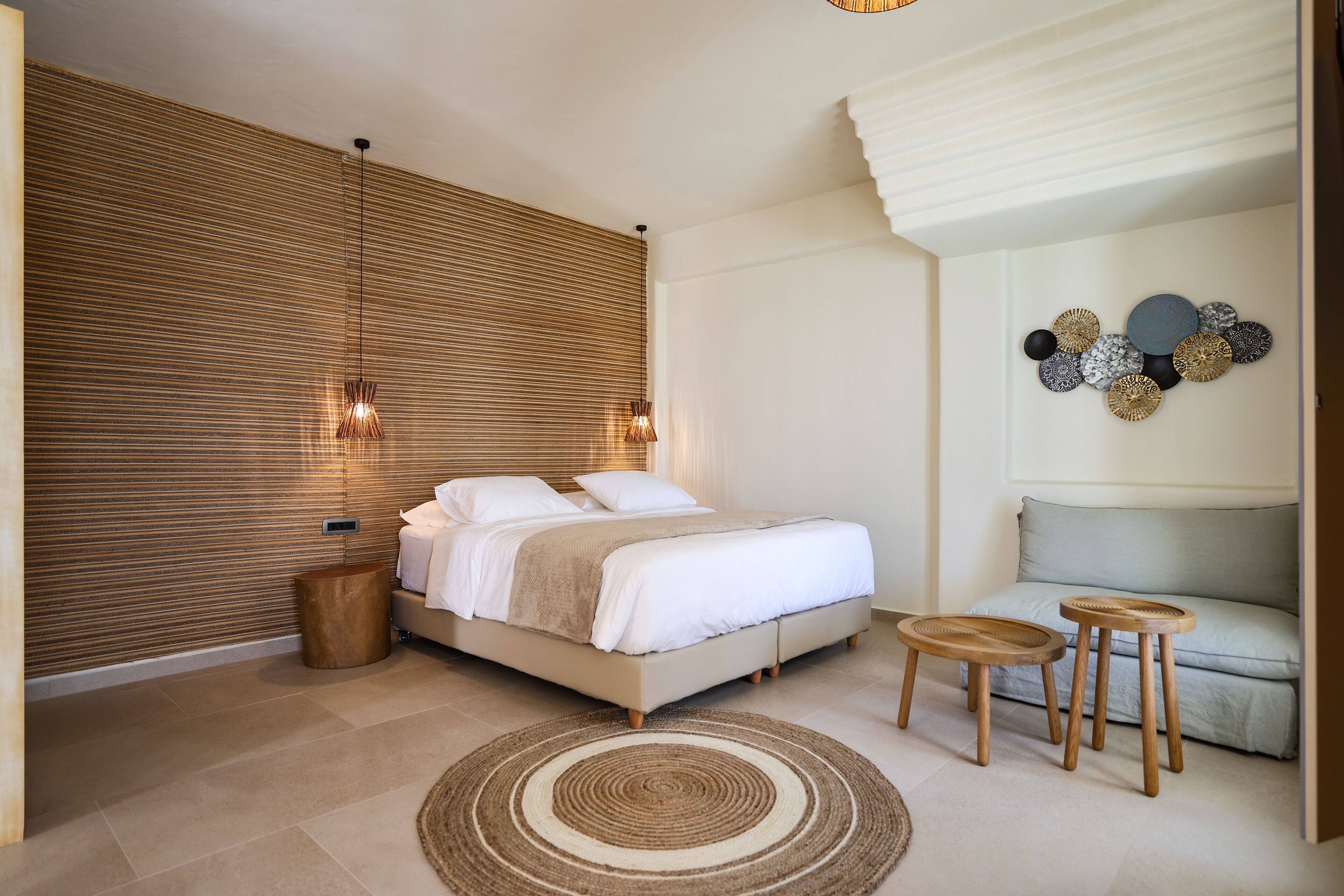 A modern bedroom with a bed, bedside tables, a wall-mounted light fixture, and a decorative wall piece.