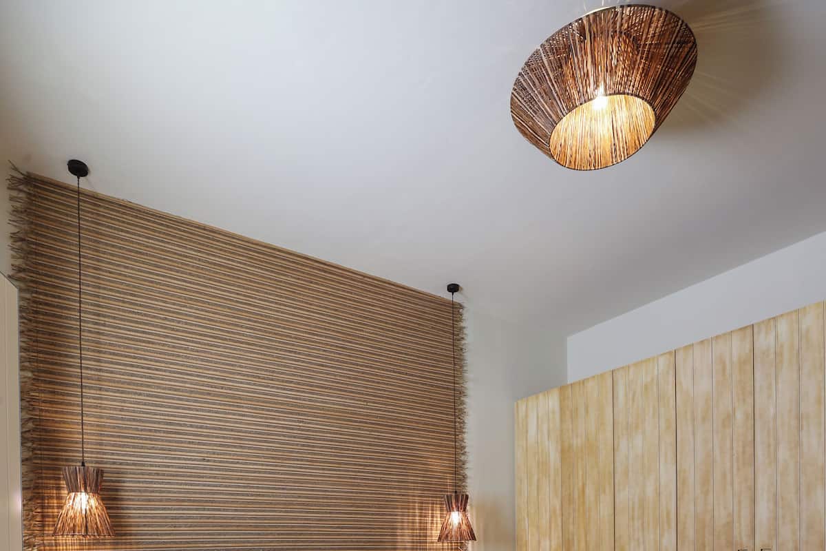 A bedroom with a large bed, wooden headboard, and a hanging light fixture.