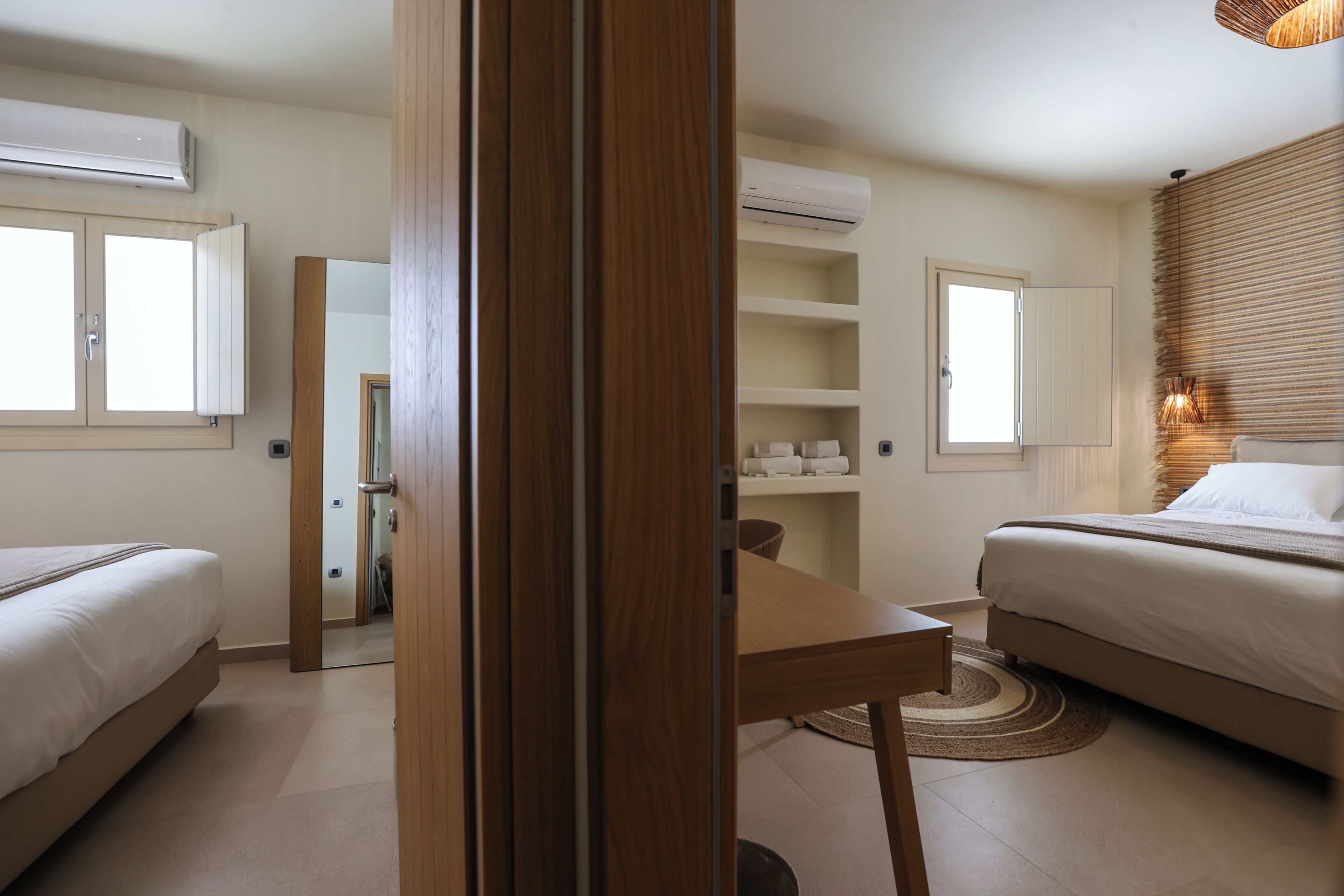Ein modernes Schlafzimmer mit zwei Betten, einem Holztisch und eingebauten Regalen.