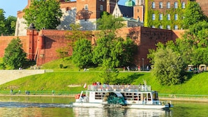 Eine historische Burg mit einem Flussboot im Vordergrund.