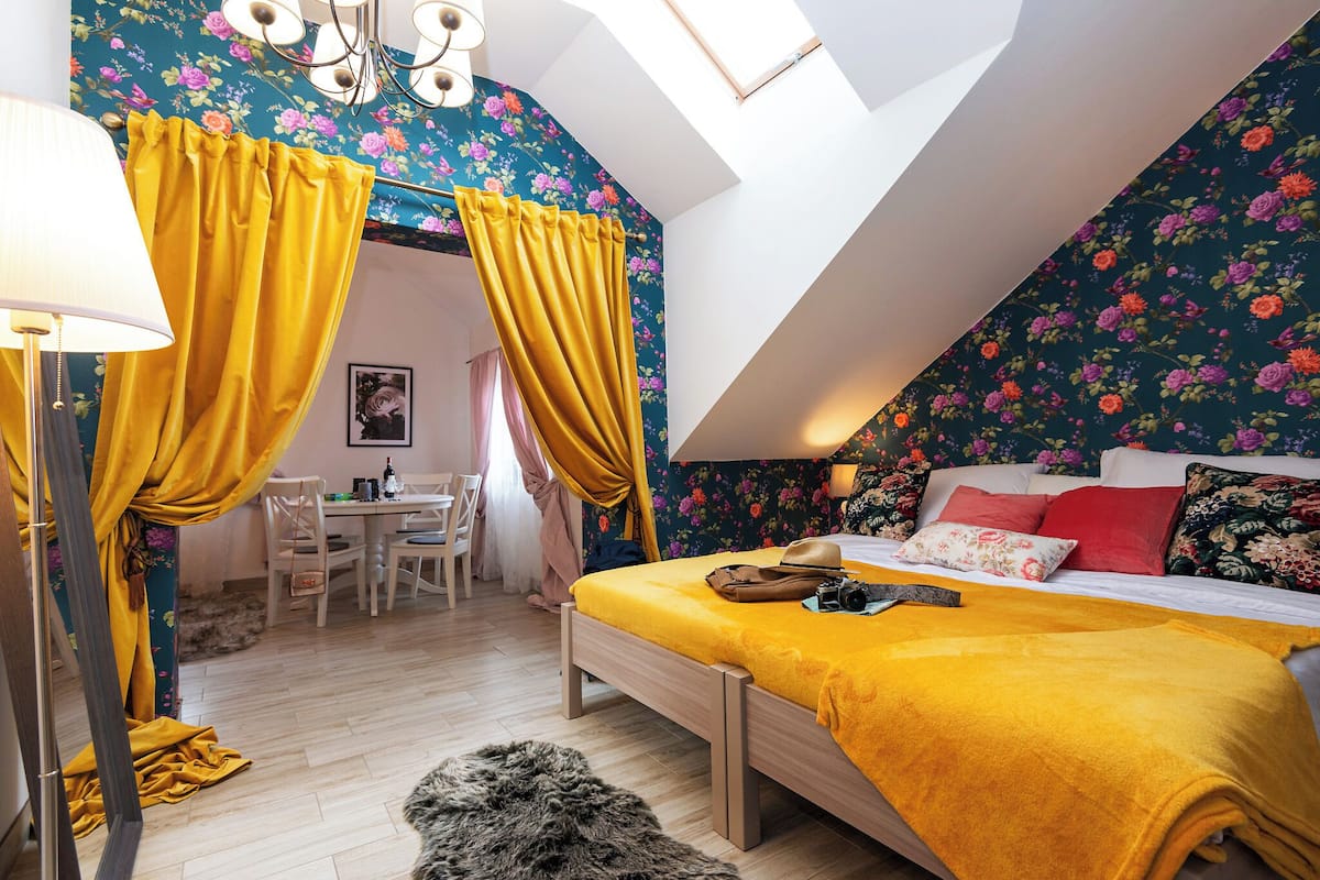 Een slaapkamer met een bed, een bureau en een stoel. Er is een raam met gordijnen.