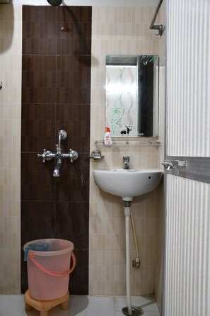 A bathroom with a shower, sink, and a mirror. - Hotel Buddha International (Patna)