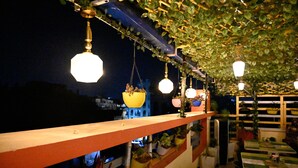 An outdoor dining area with hanging lights and potted plants. - Hotel Buddha International (Patna)