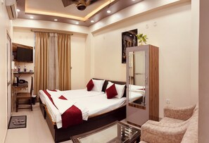 A hotel room with a large bed, a desk with a computer, a chair, a sofa, and a TV. - Hotel Buddha International (Patna)
