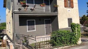 A two-story building with a balcony on the upper floor, featuring potted plants. - 2-bedroom apartment (Bosco Chiesanuova)
