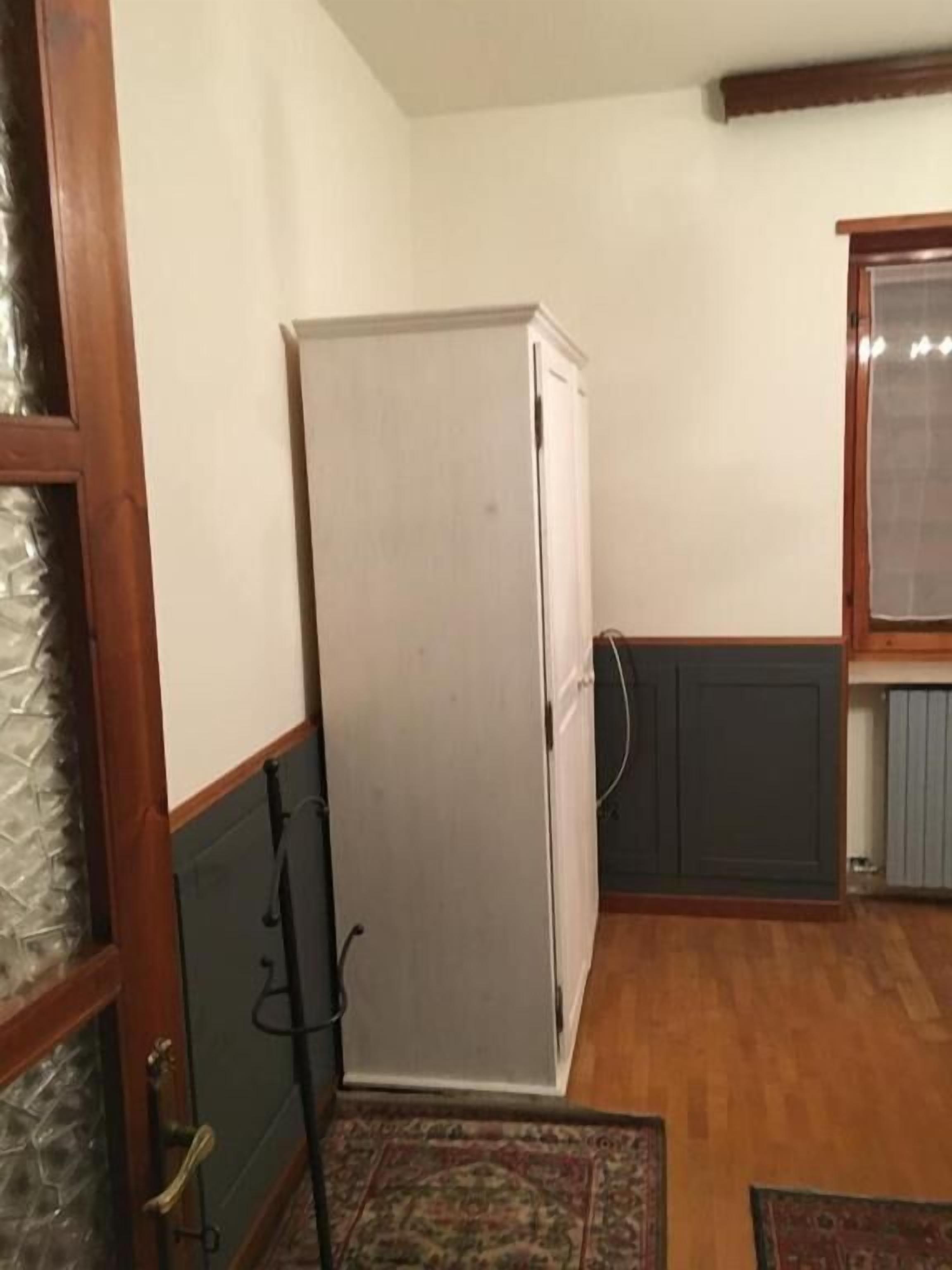A compact kitchen with a white refrigerator, wooden cabinets, and a window with a blind.