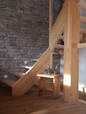 A wooden staircase with a stone wall background.