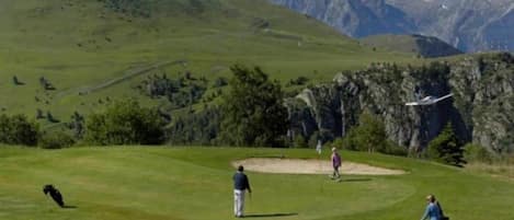 Um campo de golfe com montanhas ao fundo.