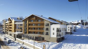A multi-story hotel with a ski lift in the background.