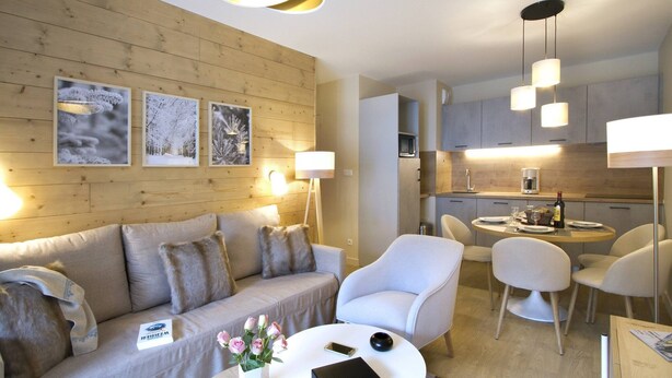 Un salon moderne comprenant un canapé, des fauteuils, une table basse et un coin repas avec une table et des chaises.