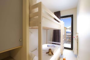 A hotel room with a bunk bed, a small table with a teddy bear, and a window with a view of a mountain. - Apartment in Éclose with Mountain Views (Huez)