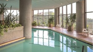 An indoor swimming pool with large windows, potted plants, and lounge chairs. - 2-bedroom condo near Sugar Mountain Resort (Sugar Mountain)
