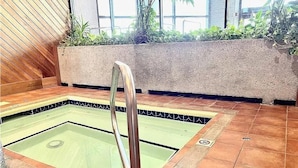 A small indoor pool with a clear glass bottom, surrounded by tiled flooring and a concrete planter with plants. - 2-bedroom condo near Sugar Mountain Resort (Sugar Mountain)