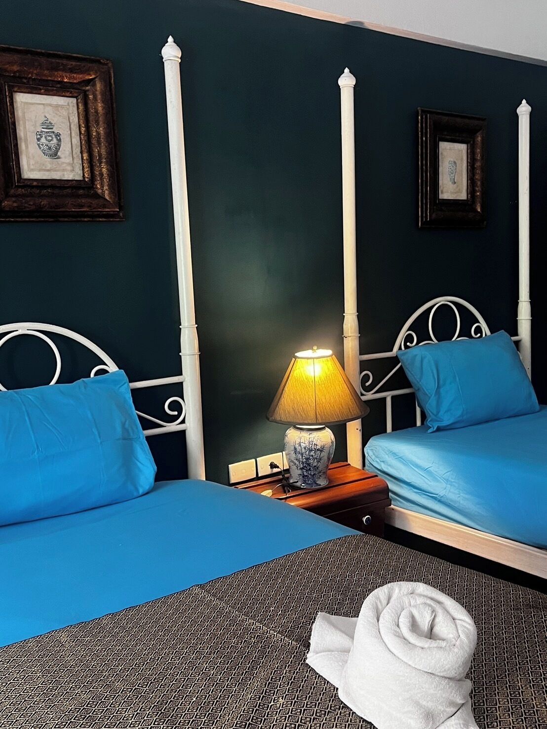 A hotel room with two beds, a nightstand with a lamp, and a towel on the floor.