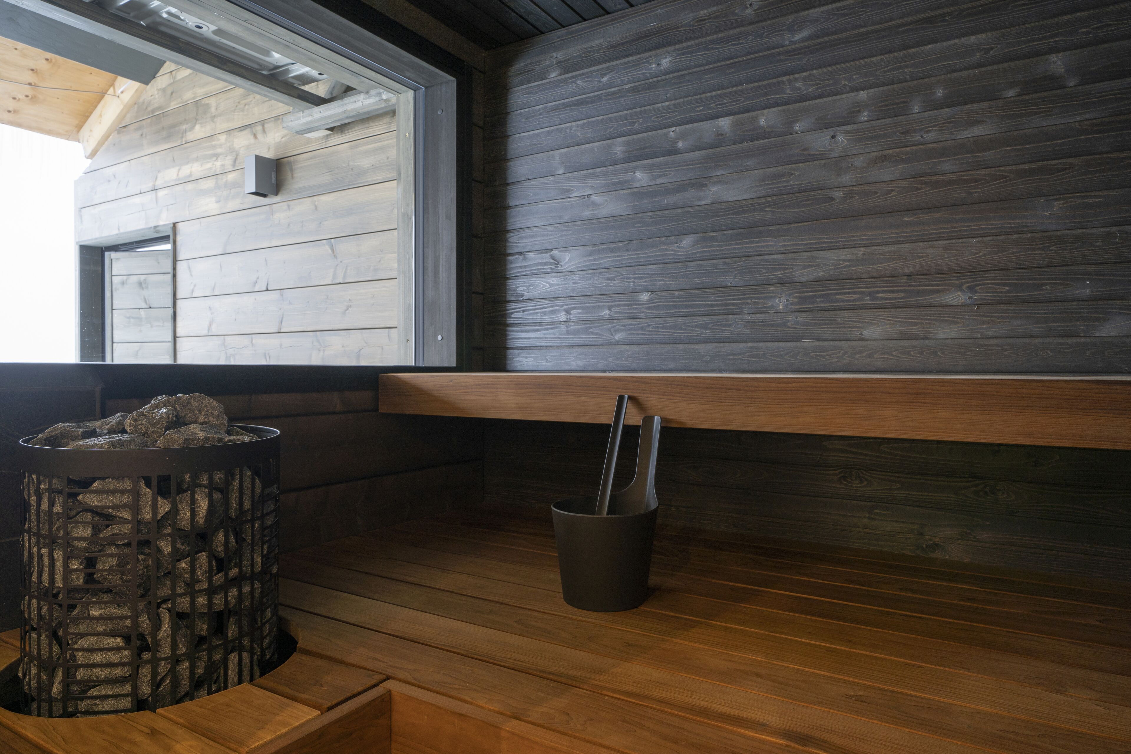 A wooden interior with a stone fire feature and a black trash bin.