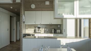Una cocina moderna con armarios blancos, techo de madera y un ventanal grande.