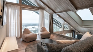 A modern loft bedroom with a sloped ceiling, large windows, and a view of a snowy landscape. - Ski-Inn Kultakero (Pyhätunturi)