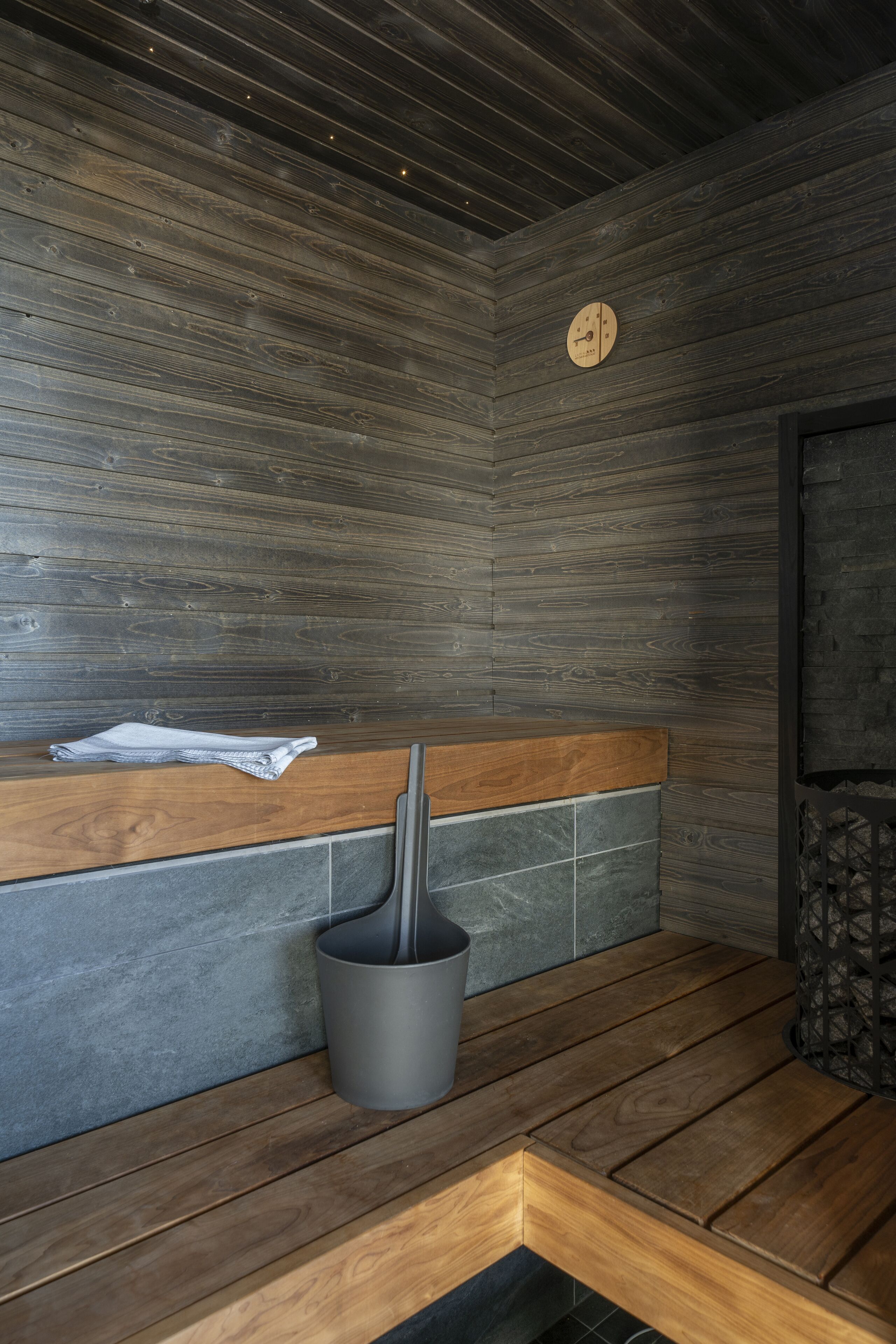 Een sauna met houten banken, een handdoek en een emmer.