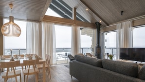 A modern living room with a sofa, dining table, chairs, and a TV. - Ski-Inn Kultakero (Pyhätunturi)
