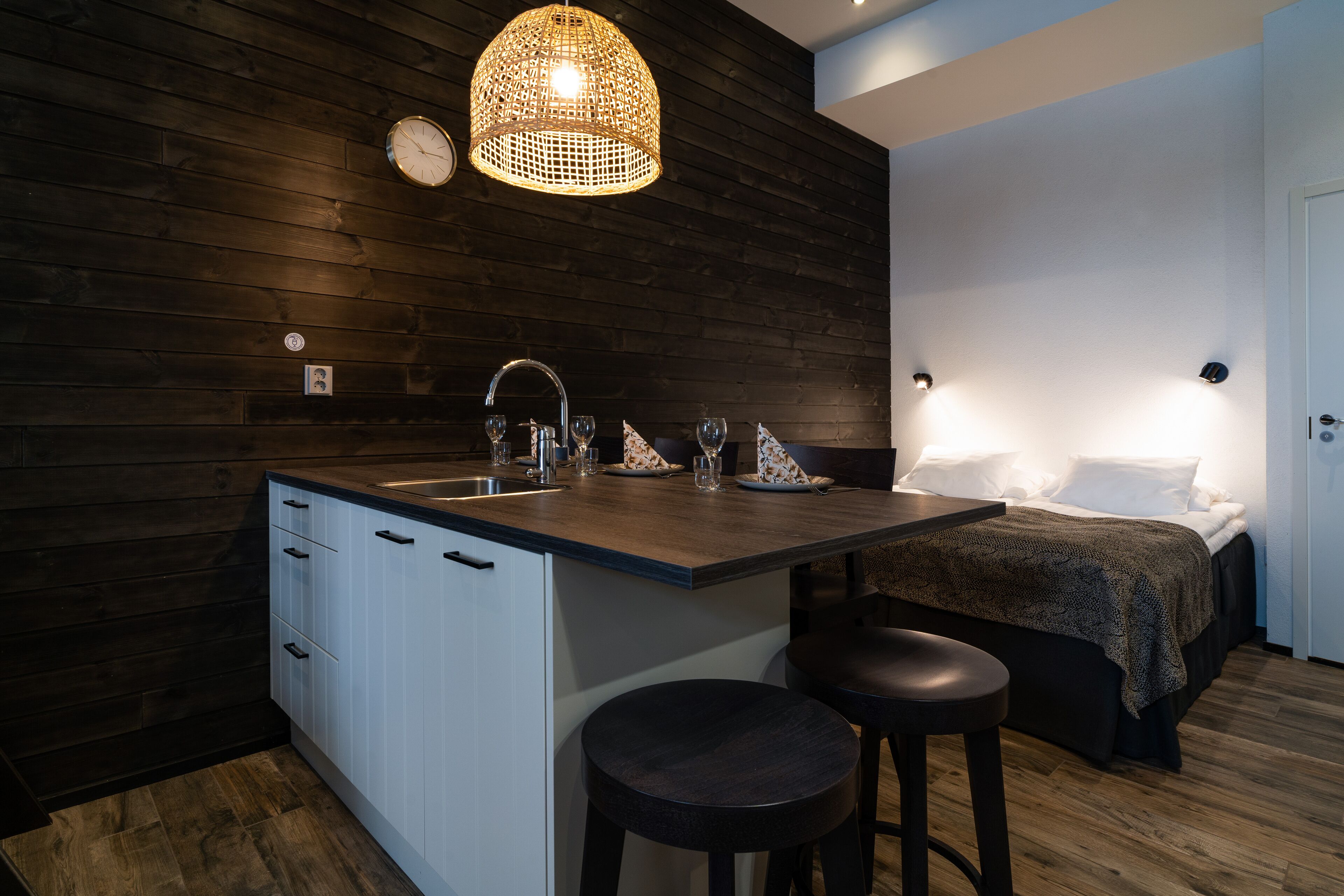Una cocina compacta con protector de encimera de madera, un lavamanos y una zona de comedor con taburetes.
