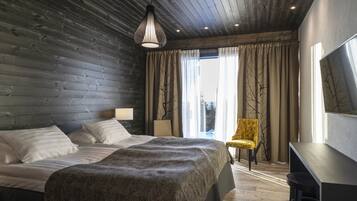 Een moderne slaapkamer met een houten hoofdbord, een groot bed met een gebloemd deken, een bureau en een stoel.