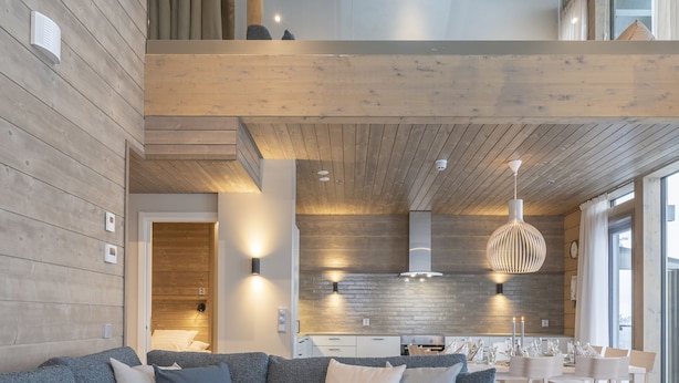 A modern living room with a sectional sofa, a round coffee table, and a dining area with a white table and chairs. - Ski-Inn Kultakero (Pyhätunturi)
