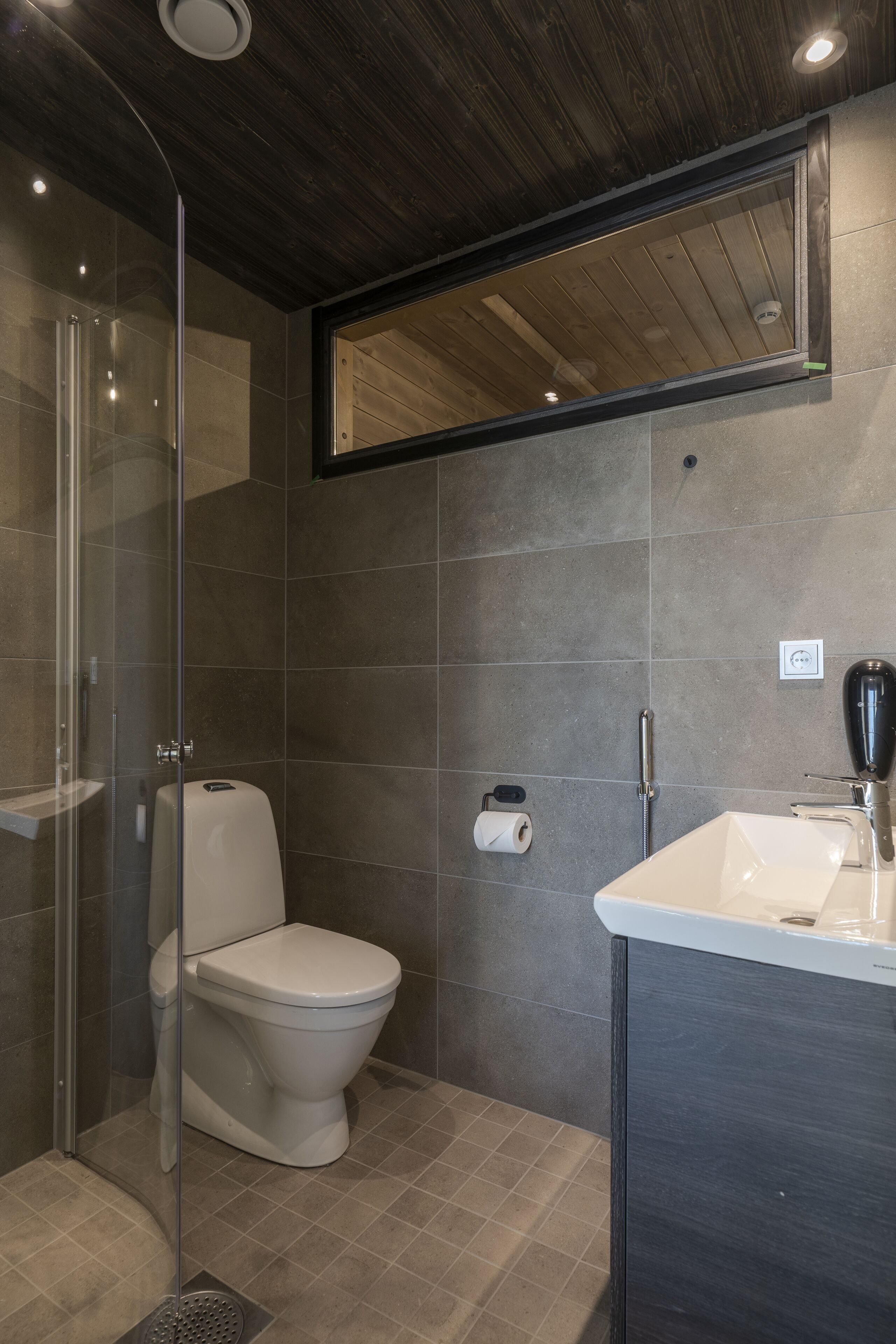 A modern bathroom with a glass-enclosed shower, a toilet, and a sink.