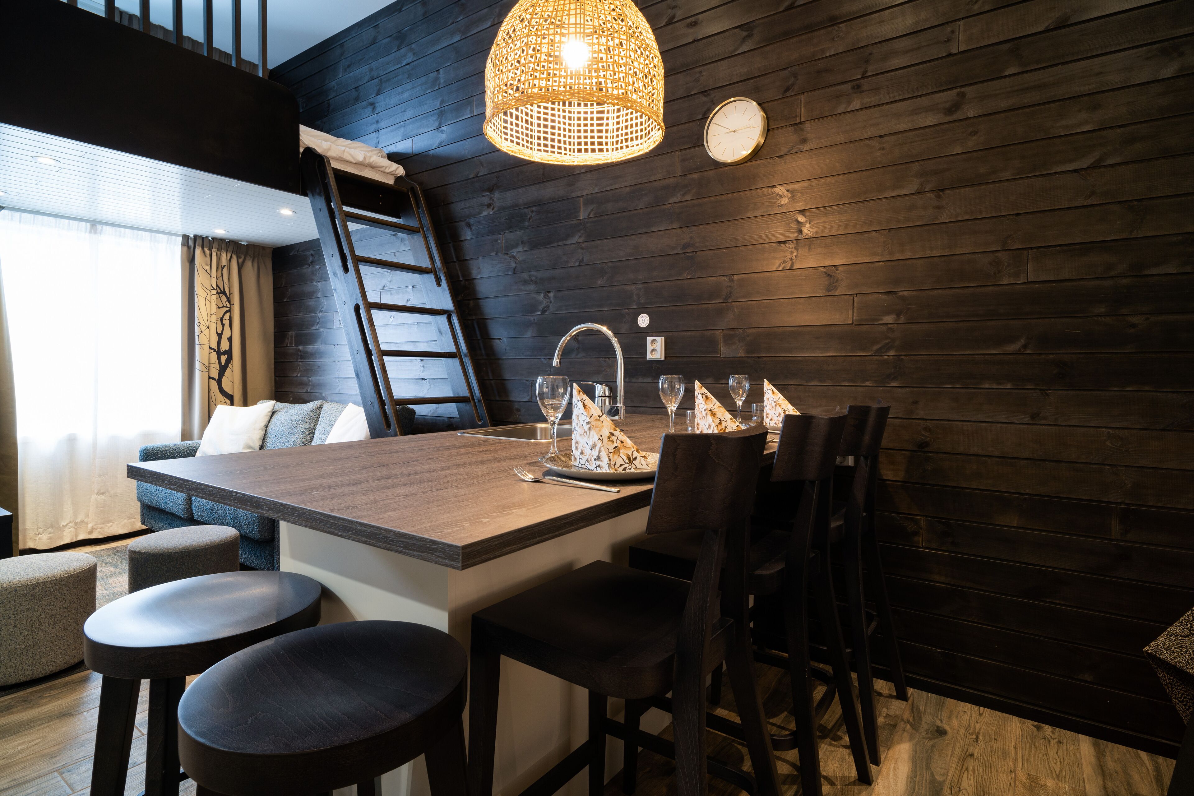 A modern kitchen with a wooden island, bar stools, and a hanging light fixture.