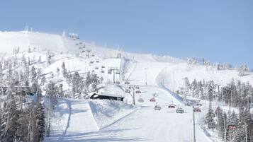 A snow-covered ski slope with ski lifts and trees.