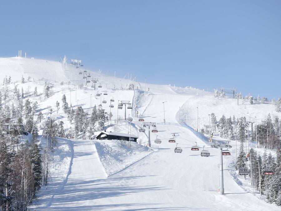 A snow-covered ski slope with ski lifts and trees.