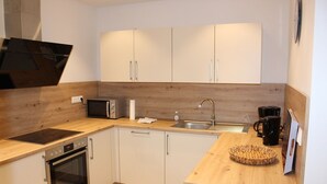 Eine kleine Küche mit Mikrowelle, Backofen, Spüle und Holz Arbeitsplatten.