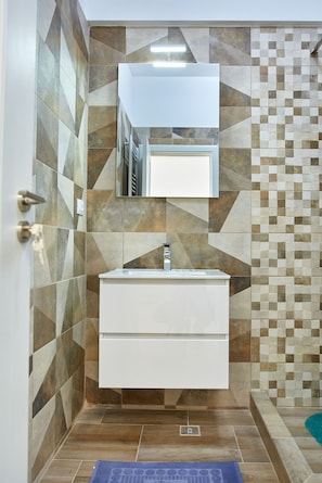 A bathroom with a geometric tile backsplash, a white vanity, and a mirror above it. - Apartamente Tomis Villa (Navodari)