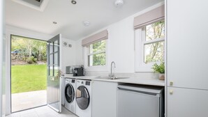 A modern kitchen with a built-in washer and dryer, a sink, and a window with a view of the garden.