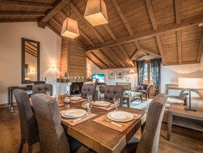A dining area with a wooden table set for six, surrounded by upholstered chairs.