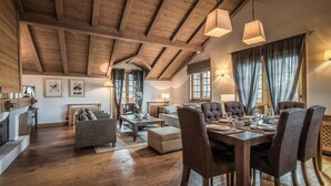 Un'ampia zona giorno con soffitto in legno a vista, un tavolo da pranzo per quattro persone e un angolo salotto accogliente.