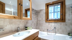 Un bagno con un mobile bagno in legno, un lavandino, una vasca e una finestra con tende.