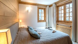 Una camera da letto con un letto, un comodino, una lampada e una finestra con tende.