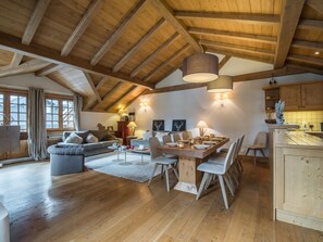 Amplia sala de estar con techo de madera alto, una mesa de comedor para cuatro personas y un rincón de descanso acogedor.