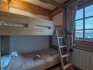 Ein Stockbett mit einer Leiter, ein Fenster mit Blick und ein Teddybär auf der unteren Schlafstelle.