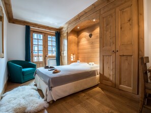 Un dormitorio acogedor con una cama, un sillón verde azulado y paredes de madera.