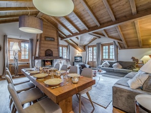 Un salón amplio con una mesa de comedor de madera dispuesta para cuatro personas, un sofá y una chimenea.