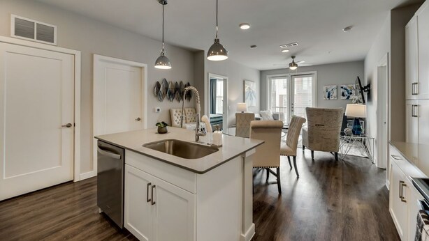 A modern kitchen with a central island, pendant lighting, and a dining area with a chair and table. - MCK203 - Apt|Patio|15mi to Toyota Stadium|Sleeps 4 (McKinney)
