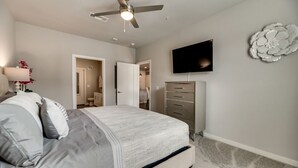 A bedroom with a bed, a ceiling fan, a TV, a dresser, and a decorative wall piece. - MCK203 - Apt|Patio|15mi to Toyota Stadium|Sleeps 4 (McKinney)